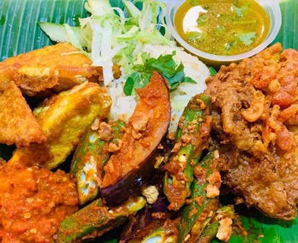 Buffet food catering featuring fried eggplant, okra, and tofu served on a traditional banana leaf. 